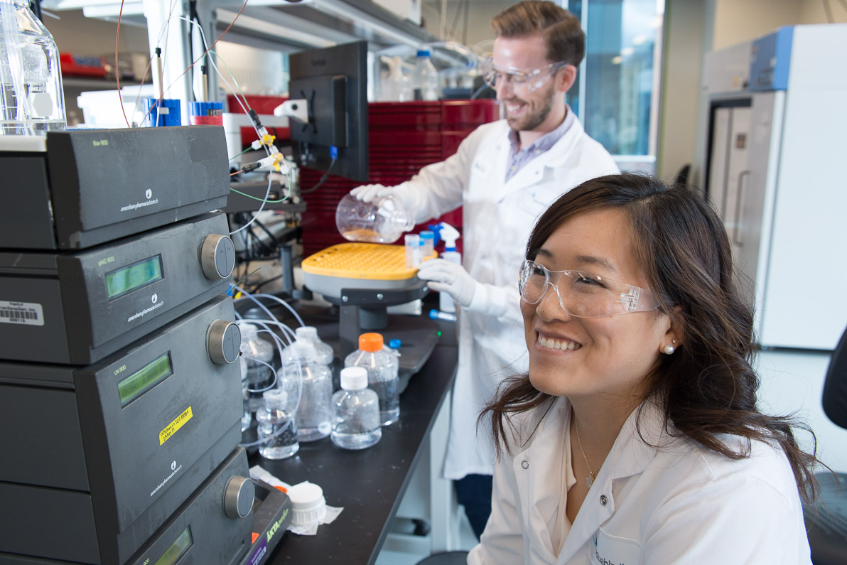 Female scientist smiling in the foreground of a lab