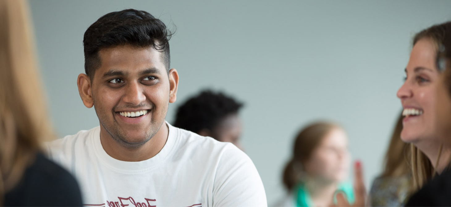 Man sitting in a group smiling and looking to his left