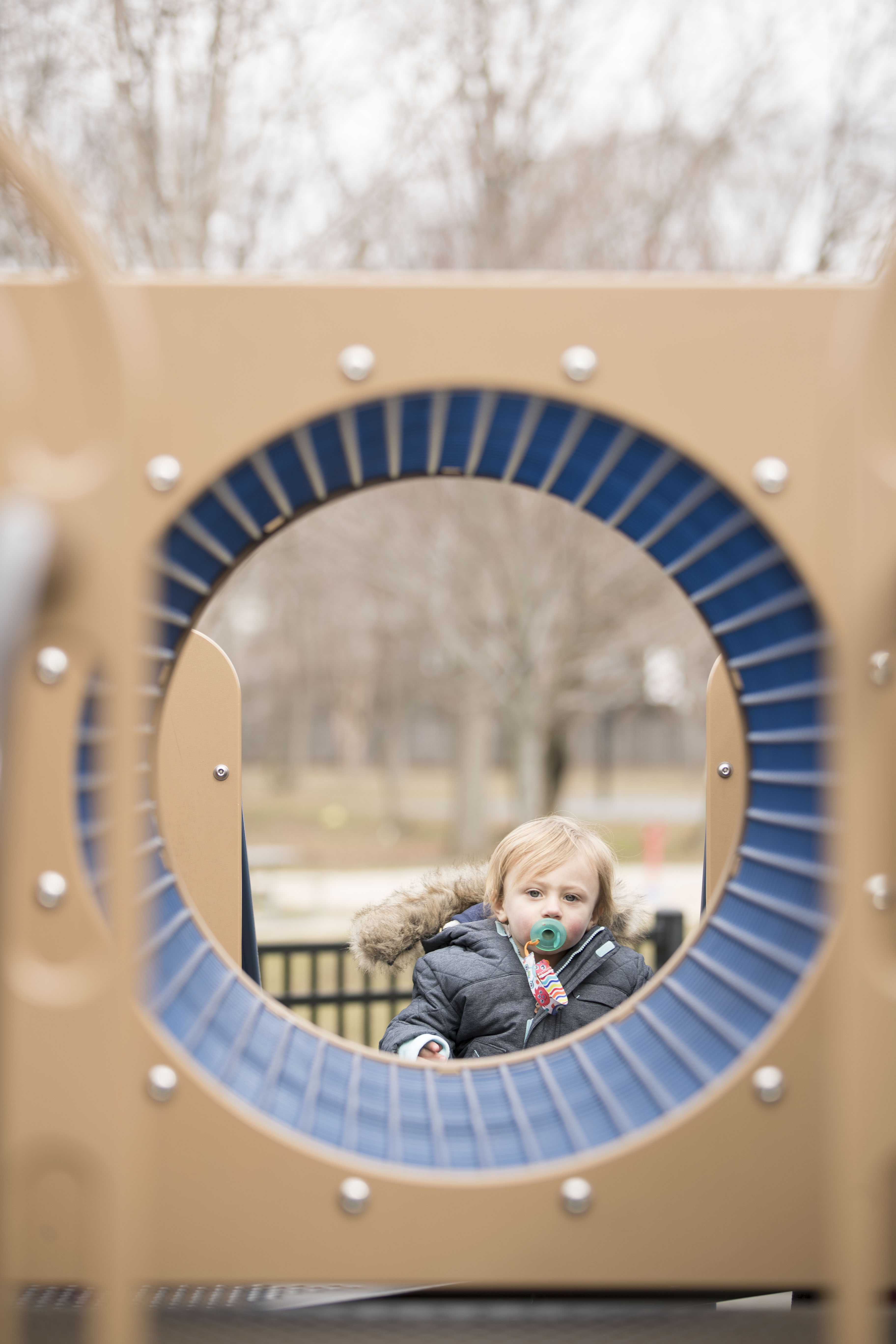 Young boy sitting on a bench through playground equipment